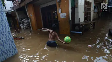 Anak-anak bermain saat banjir merendam permukiman di Kebon Pala, Jatinegara, Jakarta, Selasa (26/2/2019). Banjir setinggi 1,5 meter tersebut terjadi karena air Sungai Ciliwung meluap akibat air kiriman dari Bogor, Jawa Barat. (Merdeka.com/Imam Buhori)