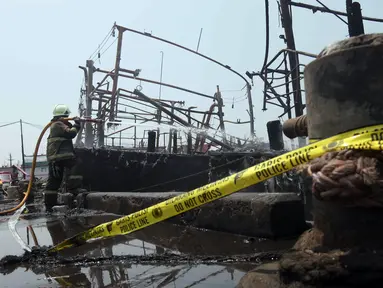 Petugas pemadam kebakaran melakukan pendinginan pada kapal yang hangus terbakar di Pelabuhan Perikanan Samudera Nizam Zachman, Muara Baru, Jakarta, Selasa (5/9/2023). (Liputan6.com/Herman Zakharia)