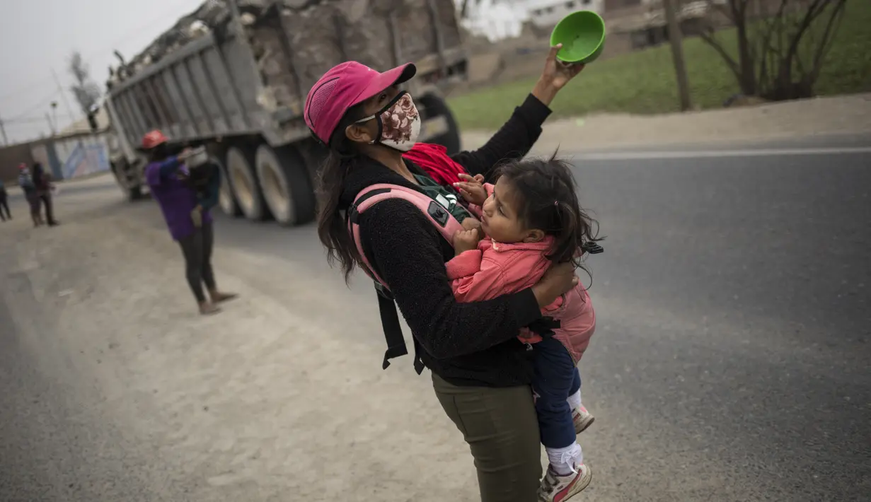 Jenny Diaz menggendong putrinya Aina Flores 1 tahun mengemis selama pandemi virus corona di tengah jalan di pinggiran Lima, Peru (22/8/2020).  (AP Photo/Rodrigo Abd)