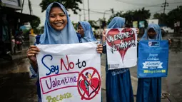 Seorang pelajar membawa spanduk saat menggelar demonstrasi menolak perayaan Hari Valentine di Surabaya, Jawa Timur, Kamis (14/2). Pelajar menilai Valentine sebagai pengaruh budaya asing. (Juni Kriswanto/AFP)