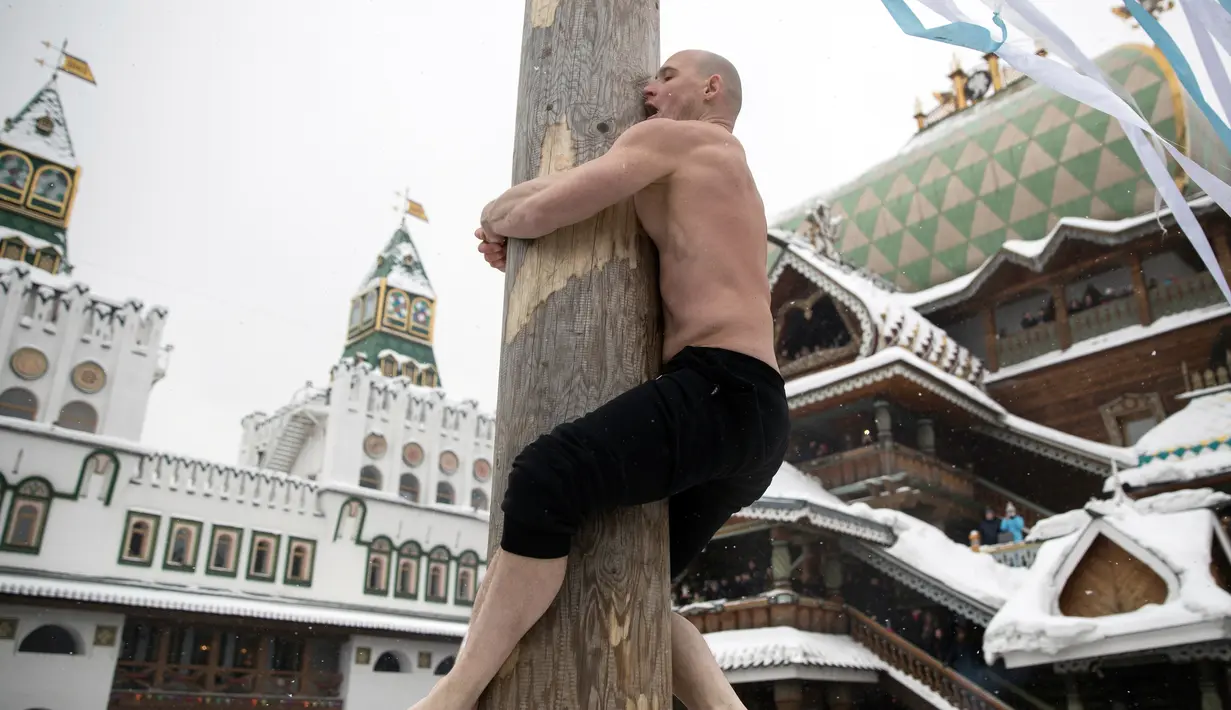 Seorang pria memanjat ke sebuah tiang saat perayaan liburan Maslenitsa (Shrovetide) di Moskow, Rusia (18/2). Maslenitsa adalah liburan tradisional Rusia dan Belarusia. (AP Photo / Pavel Golovkin)