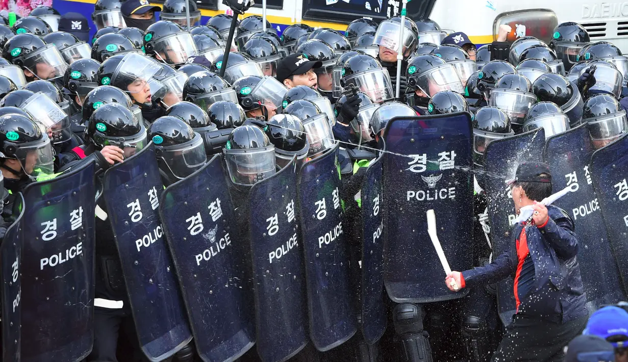 Seorang pendukung Presiden Korsel, Park Geun-hye memukul barikade polisi di Seoul, Jumat (10/3). Ribuan pendukung mengamuk menanggapi pemecatan Park Geun-hye oleh sebuah keputusan bersejarah yang dikeluarkan Mahkamah Konstitusi. (JUNG Yeon-Je/AFP)