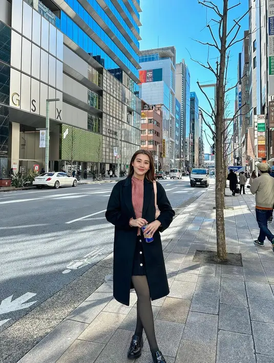 Trench coat hitam dan loafers hitam jadi sentuhan chic pada penampilan Aaliyah [@aaliyah.massaid]