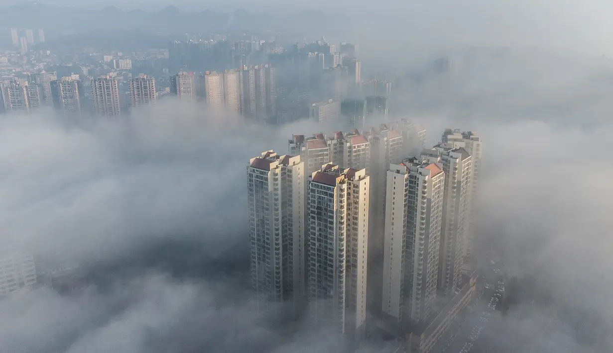 Foto udara ini menunjukkan bangunan yang diselimuti kabut pagi di Bijie, provinsi Guizhou barat daya China (18/11/2021).  Bijie memiliki iklim dataran tinggi subtropis dengan musim panas yang sangat hangat dan hujan serta musim dingin yang sejuk dan lembap. (AFP/STR)