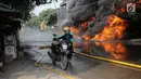 Pengemudi ojek online mendorong sebuah sepeda motor saat api melalap gudang di Jalan Kampung Bandan, Ancol, Jakarta Utara, Kamis (5/7). (Liputan6.com/Faizal Fanani)