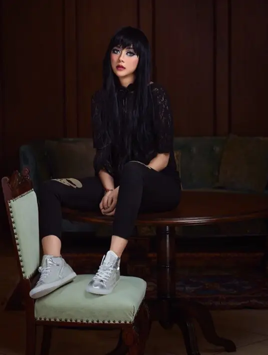 Artis Aura Kasih berpose di atas sebuah meja dengan bergaya gothic lewat lace top yang dipadukan legging dan sepatu sneakers berwarna silver. (Instagram/aurakasih)