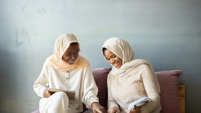 Dua wanita muslimah membaca buku