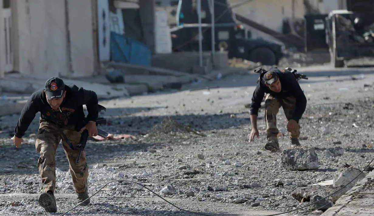 Dua tentara pasukan khusus Irak menyelamatkan diri setelah serangan bom mobil bunuh diri yang dilakukan militan ISIS di kota Tahrir, Irak, 17 November 2016. (REUTERS/Goran Tomasevic)