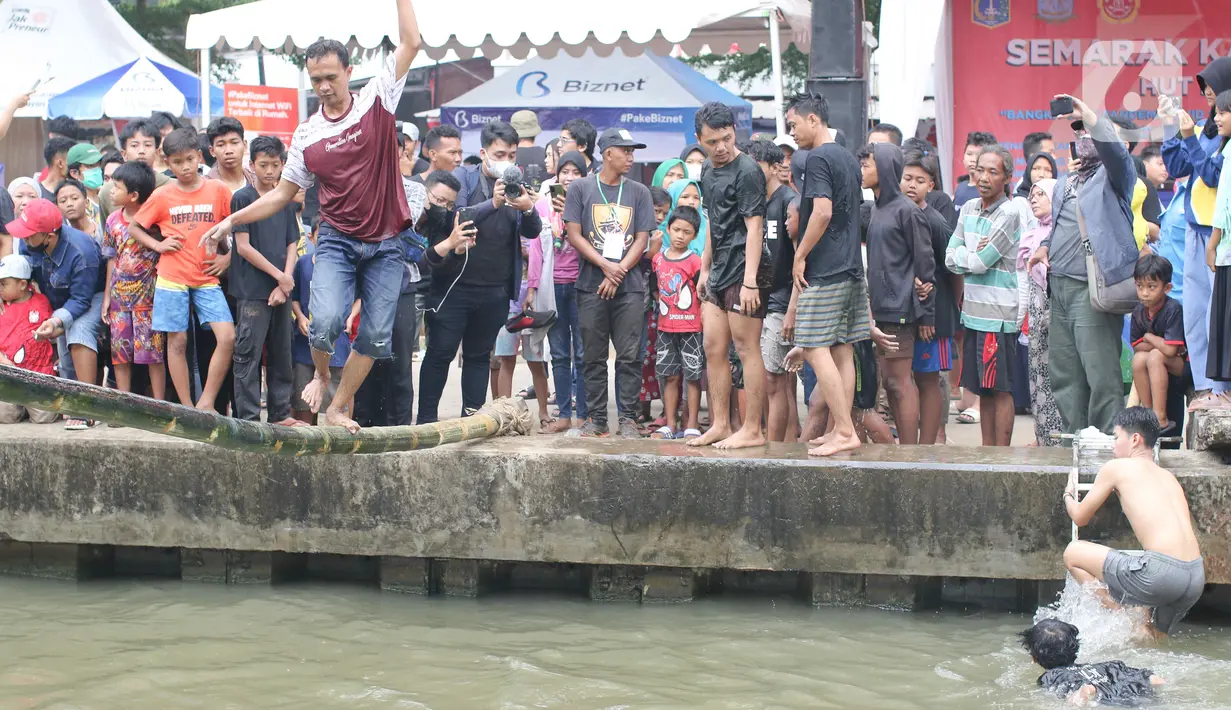 Seorang warga mengikuti perlombaan jalan di atas bambu di aliran Kalimalang, Jakarta Timur, Sabtu (27/8/2022). Perlombaan di Kalimalang yang diselenggarakan kembali setelah dua tahun berhenti akibat pandemi covid-19 ini untuk memeriahkan peringatan HUT ke-77 Kemerdekaan RI. (Liputan6.com/Herman Zakharia)