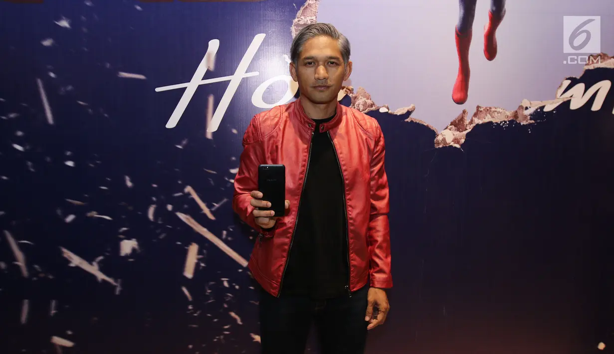 Aktor Ibnu Jamil berpose sambil menunjukan OPPO F3 Plus Black Edition di depan poster film Spiderman: Homecoming saat nobar di Gandaria City, Selasa (4/7). (Liputan6.com/Herman Zakharia)