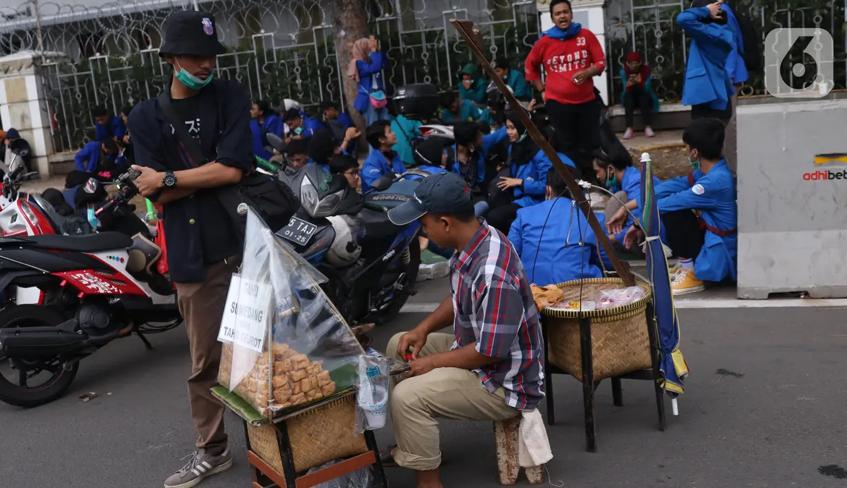 Pedangang menyiapkan makanan untuk massa aksi saat demo penolakan omnibus law di kawasan Patung Kuda, Jakarta, Selasa (20/10/2020). Para pedagang kaki lima memanfaatkan moment aksi massa untuk mencari ke untungan meskipun sangat membahayakan bagi keselamatan mereka. (Liputan6.com/Angga Yuniar)
