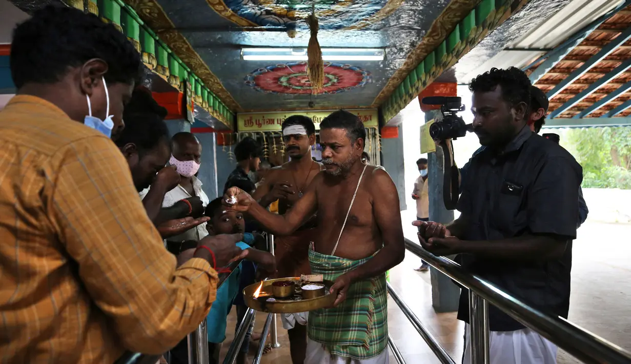 Warga desa menerima persembahan dari seorang pendeta Hindu usai berpartisipasi dalam doa khusus untuk Wakil Presiden AS terpilih Kamala Harris sebelum pelantikannya di sebuah kuil di Thulasendrapuram, selatan Chennai, Tamil Nadu, India, Rabu (20/1/2021).  (AP Photo/Aijaz Rahi)