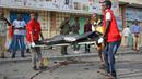 Petugas medis mengevakuasi jasad warga sipil dari lokasi ledakan bom mobil di dekat pos pemeriksaan parlemen dan Kementerian Dalam Negeri di Ibu Kota Somalia, Mogadishu, Minggu (25/3). Serangan menewaskan empat orang. (AP/Farah Abdi Warsameh)