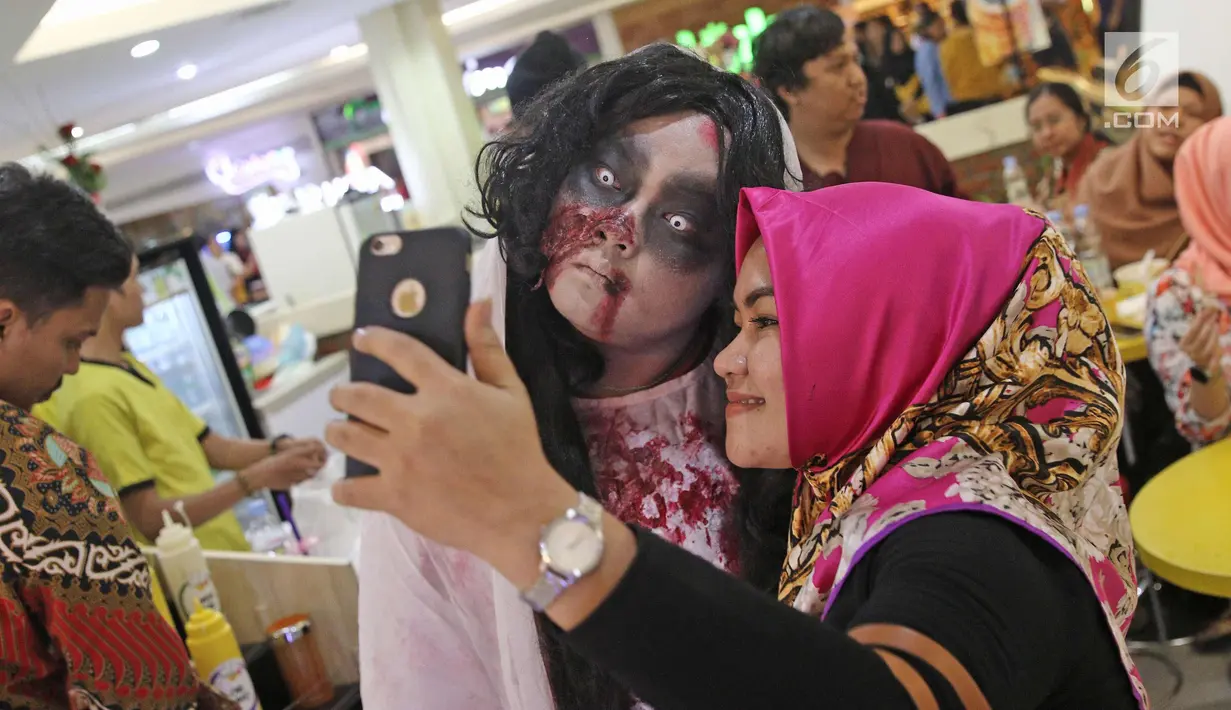 Pengunjung berselfie dengan kuntilanak di pusat perbelanjaan kawasan Sudirman, Jakarta, (31/10). Salah satu pusat perbelanjaan di kawasan Sudirman menghadirkan 3 cosplay, Zombie, Kuntilanak dan valak merayakan Halloween. (Liputan6.com/Herman Zakharia)