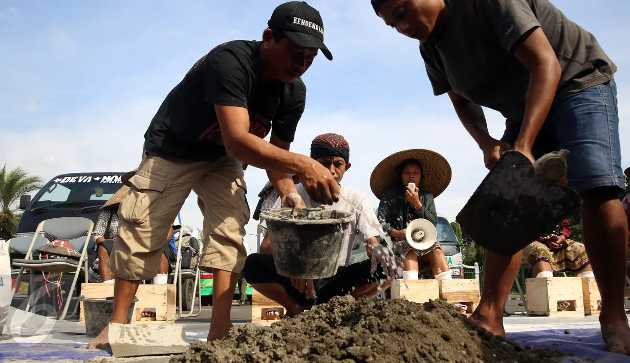 Sejumlah pria menyiapkan adonan semen jelang aksi petani Kendeng di depan Istana Negara, Jakarta, Senin (13/3). Aksi ini merupakan bentuk penolakan pembangunan pabrik semen di kawasan Rembang. (Liputan6.com/Johan Tallo)