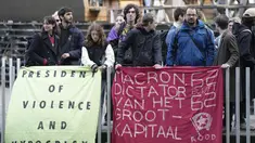Demonstran yang menentang reformasi pensiun Prancis memasang spanduk bertuliskan "Macron, diktator bisnis besar, pensiun pada usia 62 tahun akan tetap ada" saat Presiden Prancis Emmanuel Macron meninggalkan fakultas sains UVA, Universitas Amsterdam, Belanda, Rabu, 12 April 2023. (AP Photo/Peter Dejong)