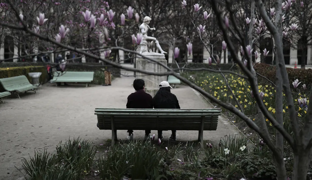 Orang-orang duduk di taman Palais Royal di Paris (22/3/2021).  Penduduk Paris dan beberapa wilayah Prancis lainnya menghabiskan akhir pekan pertama mereka di bawah penguncian terbatas selama sebulan.  (AP Photo/Lewis Joly)