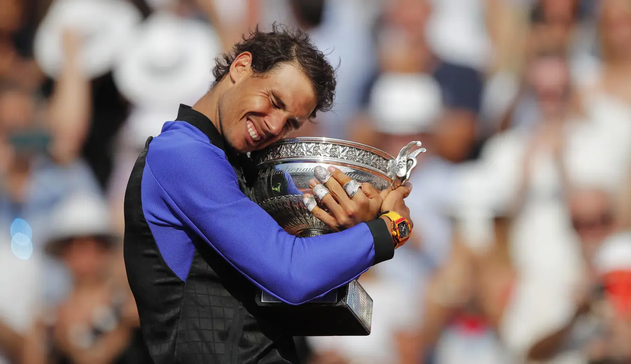 Rafael Nadal memeluk trofi juara usai mengalahkan petenis Swis, Stan Wawrinka  pada laga Final Tunggal Putra, Prancis Terbuka 2017 di Roland Garros stadium, Paris, (11/6/2017). Nadal menang  6-2, 6-3, 6-1. (AP/Christophe Ena)