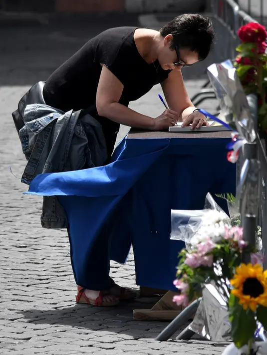 Seorang wanita menandatangani buku belasungkawa di depan Kedutaan Besar Perancis di Roma, Italia (15/7). Sedikitnya 84 orang tewas dan ratusan lainnya luka akibat hantaman truk tersebut.  (AFP PHOTO/TIZIANA FABI)