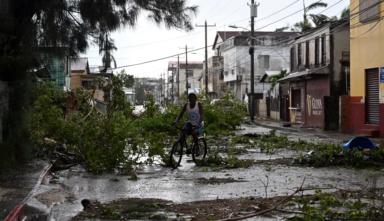 Seorang pria bersepeda melewati jalan yang terhalang oleh cabang-cabang pohon tumbang setelah Badai Lisa di Ladyville, dekat Belize City, Belize, 3 November 2022. Badai Tropis Lisa menyebabkan banjir dan membuat sebagian negara itu menjadi gelap gulita. (Johan ORDONEZ/AFP)