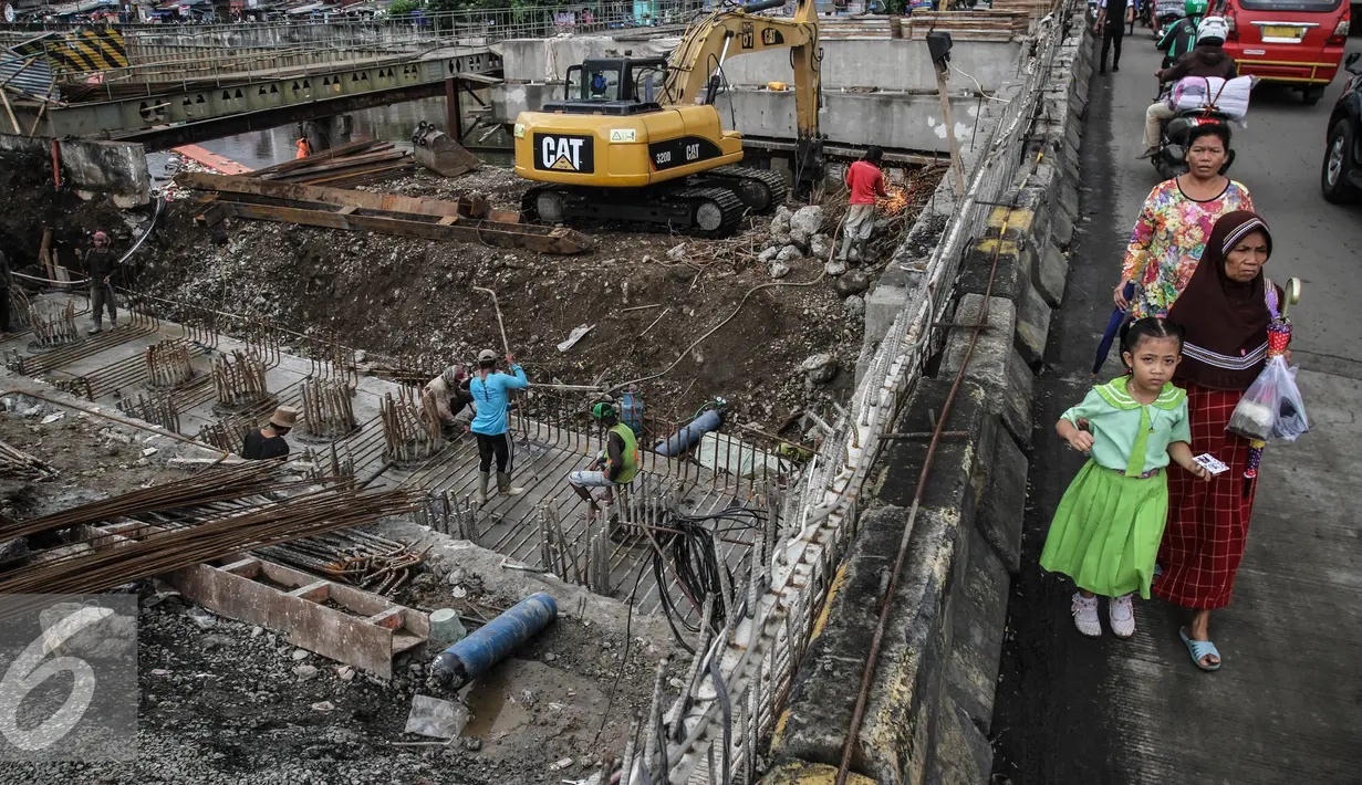 Sejumlah warga melintas di samping perbaikan jalan di kawasan Latumenten, Jakarta, Senin (05/12). Perbaikan jalan dengan mengganti pondasi baru tersebut guna memperkuat ketahanan badan jalan. (Liputan6.com/Faizal Fanani)