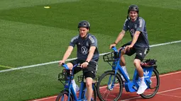 Bek Jerman Marcel Halstenberg (kiri) dan Mats Hummels (kanan) tiba dengan sepeda untuk sesi latihan latihan menjelang UEFA EURO 2020 di World of Sports Campus di Herzogenaurac (11/6/2021). Jerman berada di grup F Euro 2020 bersama Portugal, Prancis dan Hungaria. (AFP/Christof Stache)