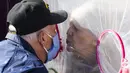 Betty Van Putten (kanan) bergerak untuk mencium suaminya melalui tenda pelukan di komunitas Crossroads Senior Living di Lakewood, Colorado, Jumat (26/2/2021). Tenda dengan penghalang plastik memungkinkan anggota keluarga terhubung secara fisik satu sama lain. (Michael Ciaglo/Getty Images/AFP)
