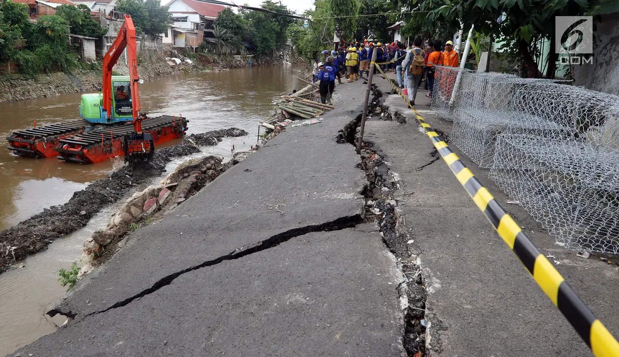 Petugas memperbaiki jalan retak di Kelurahan Kebon Manggis, Kecamatan Matraman, Jakarta Timur, Jumat (16/2). Retakan jalan bertambah panjang sekitar 25 meter setelah beberapa hari sebelumnya mengalami retakan sekitar 100 meter. (Liputan6.com/Johan Tallo)