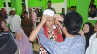 Seorang santri memakaikan peci atau kopyah kepada Ganjar Pranowo saat kunjungan ke pesantren El Bayan, Majenang, Cilacap. (Liputan6.com/Muhamad Ridlo)