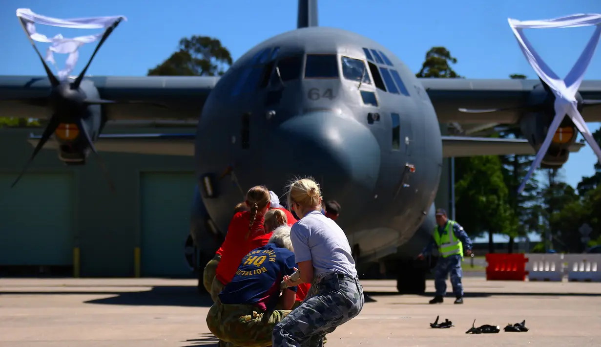 Para anggota Royal Australian Air Force menarik sebuah pesawat Hercules C-130J saat mengikuti lomba ketangkasan di Pangkalan Udara Richmond, Sydney (24/11). Lomba ini sebagai kegiatan melatih ketangkasan sekaligus kebersamaan. (REUTERS/David Gray)