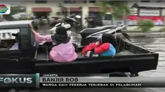 Pekerja yang mengendarai sepeda motor terpaksa harus mendorong kendaraan mereka karena mogok saat menerobos genangan.