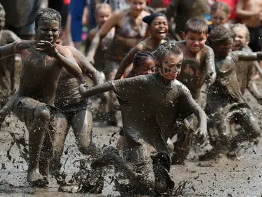 Anak-anak berlari ke dalam kubangan berisi lumpur saat Mud Day atau Hari Lumpur di Michigan, negara bagian AS, Selasa (9/7/2019). Para peserta perayaan yang menjadi tradisi setiap tahun ini merupakan anak-anak untuk agar mereka bersenang-senang selama liburan musim panas.  (AP/Carlos Osorio)