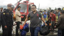 Petugas membawa barang milik korban tewas jatuhnya helikopter, di sebelah utara Ibu Kota Nepal, Kathmandu, Senin (8/8). Helikopter yang mengangkut enam warga lokal menuju Kathmandu itu hilang kontak 30 menit setelah lepas landas. (AFP PHOTO/BIKASH Karki)