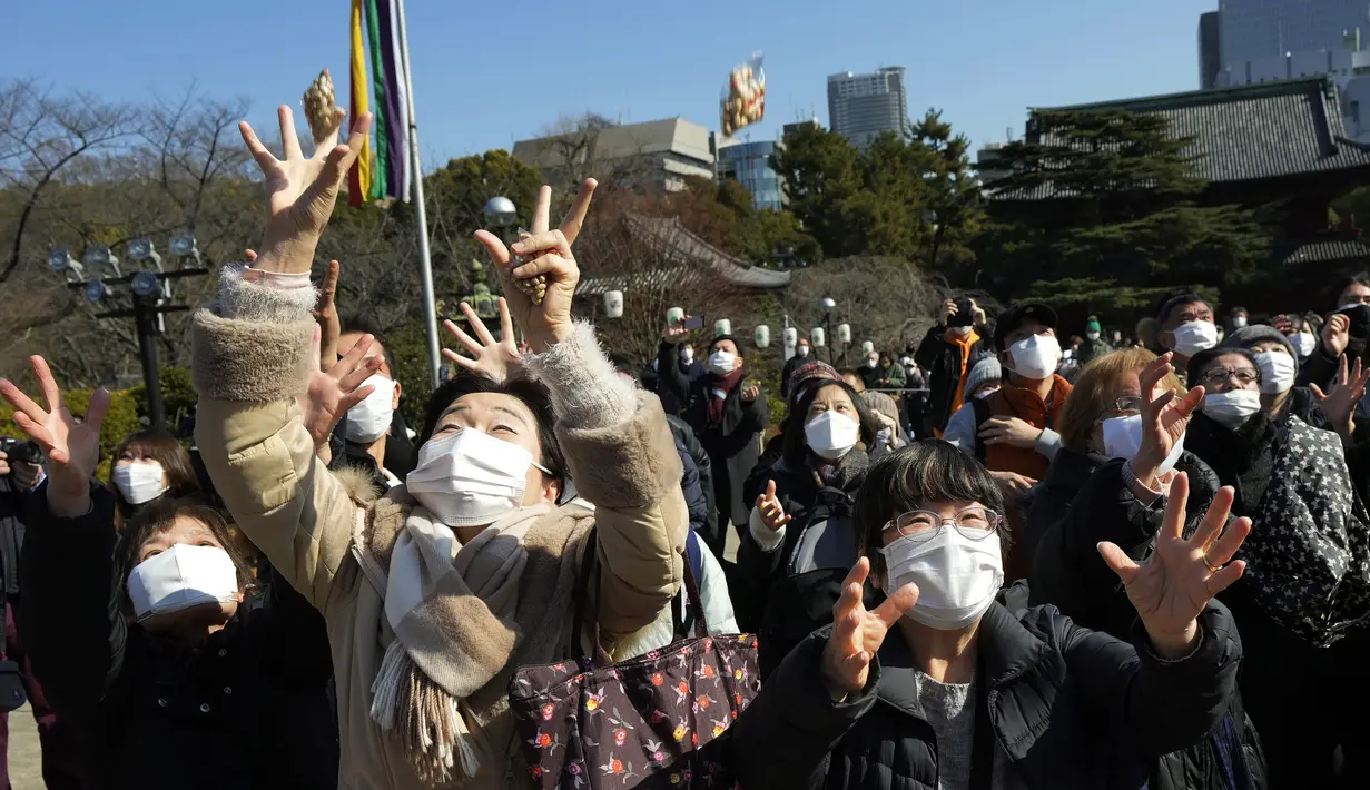 Orang-orang mencoba menangkap kacang keberuntungan yang disebarkan pada "Mame-maki," upacara pelemparan kacang di kuil Buddha Zojoji di Tokyo, 3 Februari 2022. Ritual yang diyakini membawa keberuntungan dan mengusir kejahatan dilakukan setiap tahun untuk menandai awal musim semi. (AP/Eugene Hoshiko)
