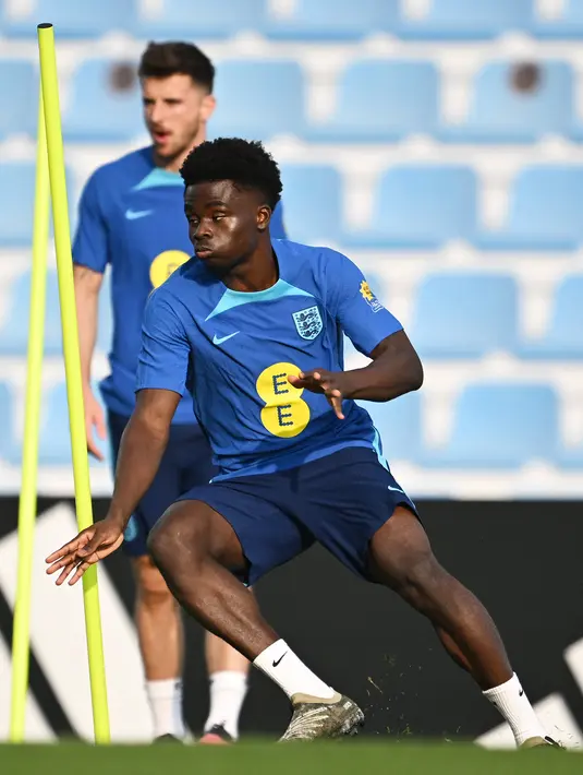 Penyerang Inggris Bukayo Saka mengikuti sesi latihan jelang bertemu Prancis pada babak perempat final Piala Dunia 2022, di Stadion Al Wakrah SC di Al Wakrah, selatan Doha, Rabu (7/12/2022). Perjalanan Inggris di Piala Dunia 2022 terbilang positif, pasalnya mereka belum terkalahkan dan hanya meraih imbang. (Paul ELLIS / AFP)
