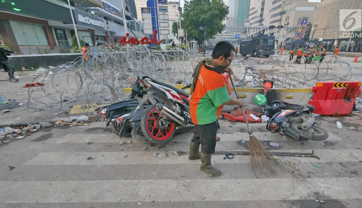 Petugas Penanganan Prasarana dan Sarana Umum (PPSU) atau Pasukan Oranye membersihkan sisa puing-puing pasca kerusuhan di MH. Thamrin, Kamis (23/5/2019). Bentrokan terjadi setelah pihak kepolisian berupaya membubarkan massa aksi yang masih bertahan di depan Bawaslu. (Liputan6.com/Herman Zakharia)