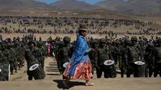 Seorang fotografer wanita pribumi suku Aymara melintas di depan barisan pasukan militer saat peringatan ulang tahun tentara Bolivia ke-192 di Kjasina, Bolivia (7/8). (AP Photo/Juan Karita)