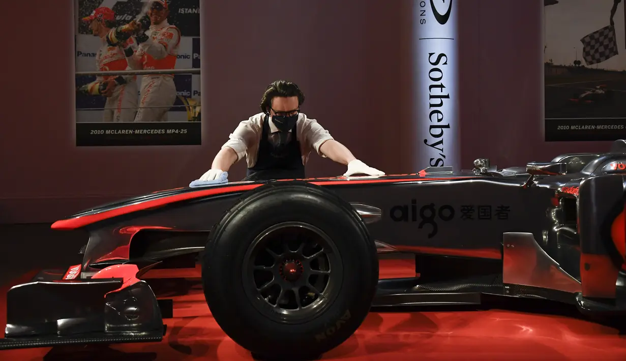 Seorang staf memoles mobil McLaren MP4-25A Mercedes yang dikendarai Lewis Hamilton pada GP Turki 2010, di Sotheby London, Selasa (18/5/2021). Mobil McLaren tersebut  akan dilelang di Grand Prix (GP) Inggris pada bulan Juli 2021 mendatang. (AP Photo/Alberto Pezzali)