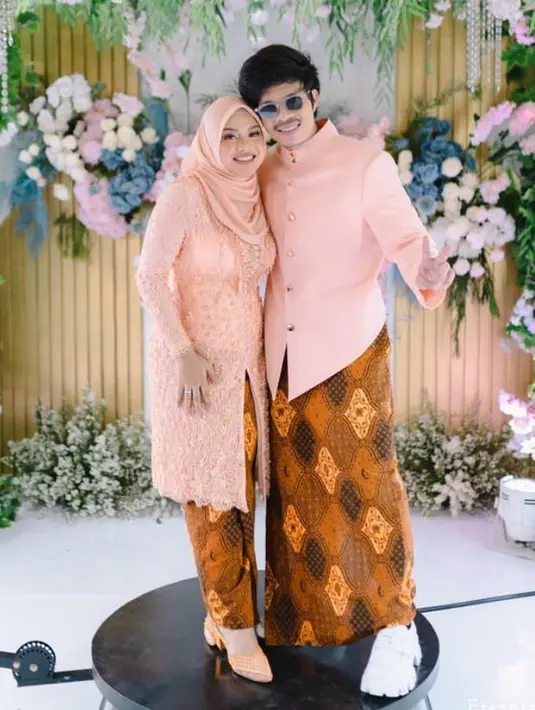 Kebaya warna peach Aurel Hermansyah cocok untuk lamaran bagi yang mengenakan hijab. Kebaya brokat berpayet senada dengan kerudung satin polos serta kitten heels tertutupnya. Dipadukan bawahan kain batik senada dengan Atta.  [@askyfebrianti]