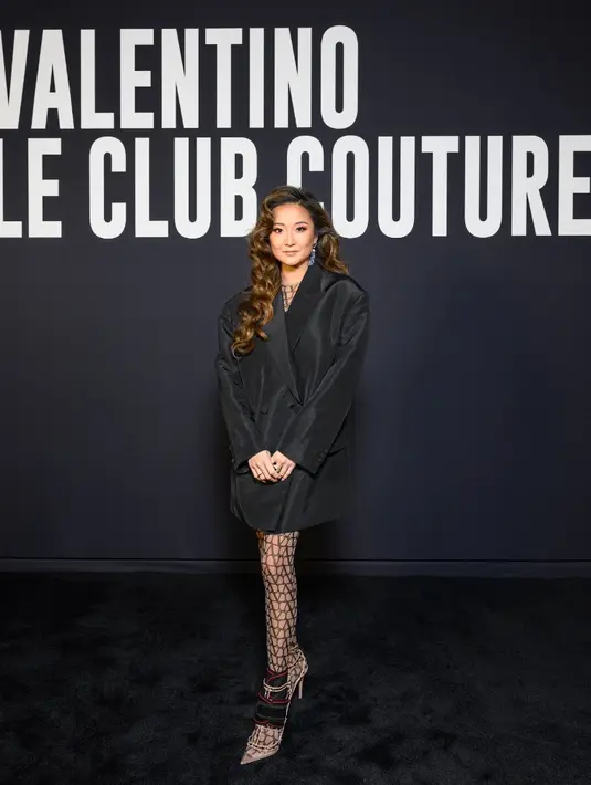 Ashley Park tampil serba hitam mengenakan long blazer dari koleksi Spring Summer 2023 Unboxing. Atasan tersebut dipadukan dengan stocking jaring dan heels dari Valentino Garavani. Credit: Valentino/SGP Italia