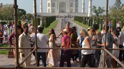 Turis melewati reruntuhan puing-puing pilar Taj Mahal yang roboh di pintu masuk bangunan ikonik tersebut di Agra, India, Kamis (12/4). Angin kencang dengan kecepatan 130 kilometer per jam menyebabkan pilar setinggi 4 meter itu runtuh. (AP/Pawan Sharma)