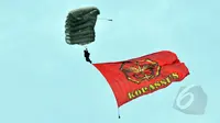 Seorang anggota membawa bendera Kopassus saat melakukan aksi terjun payung 18 lapis dalam perayaan HUT ke-63 satuan elite baret merah tersebut di Cijantung, Jakarta, Rabu (29/4/2015). (Liputan6.com/Herman Zakharia)