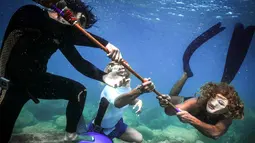 Orang-orang yang mengenakan kostum Halloween berinteraksi saat berenang di sepanjang pantai kota Batroun, Lebanon utara, Kamis (28/10/2021). Setiap tanggal 31 Oktober berbagai orang di belahan dunia biasa merayakan Halloween, hari yang identik dengan horor dan hal menakutkan. (Ibrahim Chalhoub/AFP)