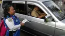 Petugas Dinas Perhubungan membagikan selebaran sosialisasi pemberlakuan sistem ganjil genap di pintu masuk Gardu Tol Cibubur 2, Jakarta, Senin (16/4). (Liputan6.com/Faizal Fanani)