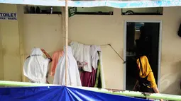 Dua orang pedagang wanita terlihat tengah bersiap untuk sholat di depan toilet umum di Pasar Blok G, Tanah Abang, Jakarta, (8/7/2014). Mereka beralasan karena lebih dekat dengan lokasi mereka berjualan (Liputan6.com/ Faizal Fanani)