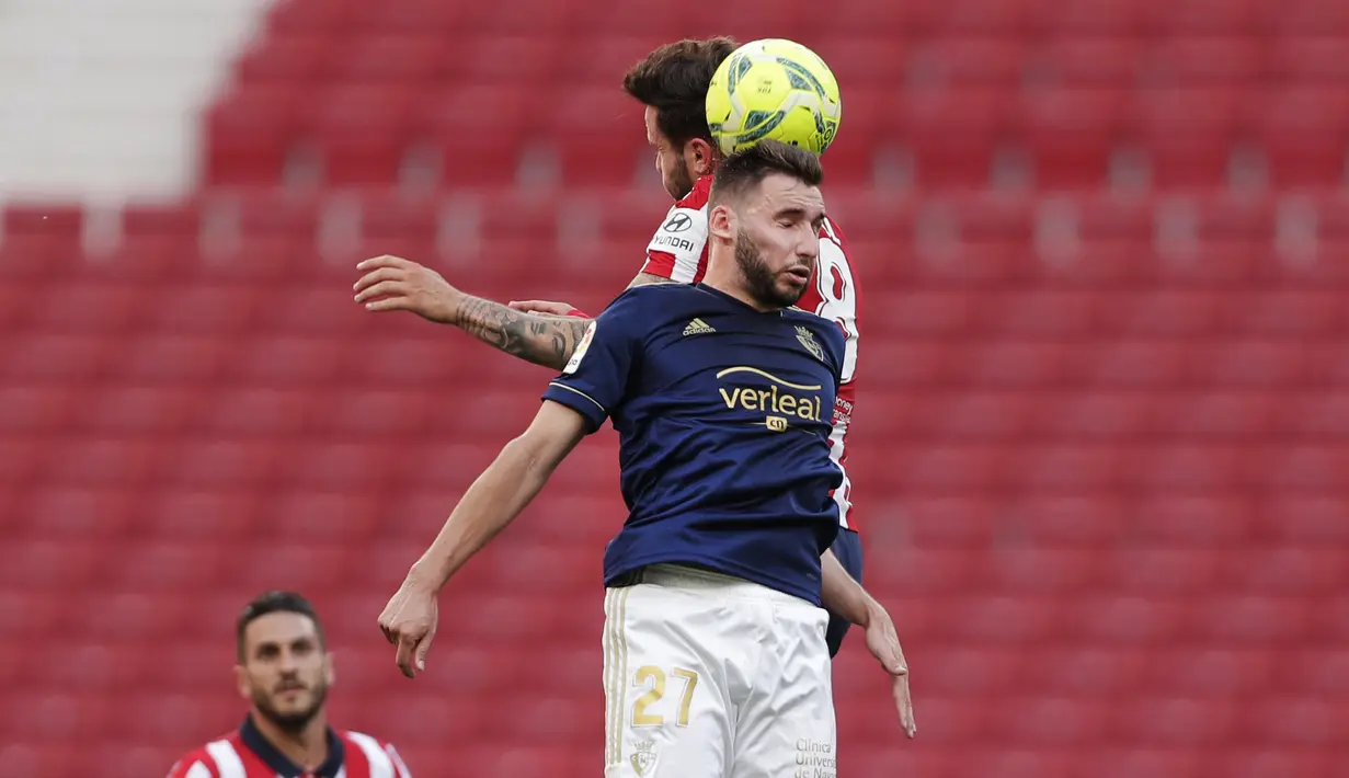 Pemain depan Osasuna, Jon Moncayola, menyundul bola saat bersaing dengan gelandang Atletico Madrid, Saul pada laga pekan ke-37 LaLiga di Wanda Metropolitano, Minggu (16/5/2021). Sempat tertinggal,  Atletico Madrid menang dramatis 2-1 atas Osasuna. (AP Photo/Manu Fernandez)