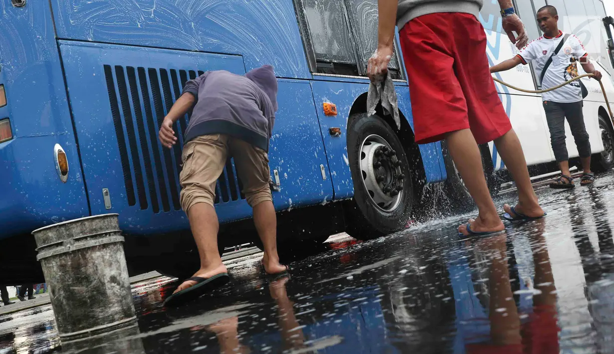 Suporter Persija Jakarta mencuci bus transjakarta di kantor PT Transjakarta, Jakarta, Kamis (13/12). Hal tersebut dilakukan bentuk tanggung jawab atas aksi vandalisme oknum suporter saat Persija meraih Juara Liga 1 2018. (Liputan6.com/Immanuel Antonius)