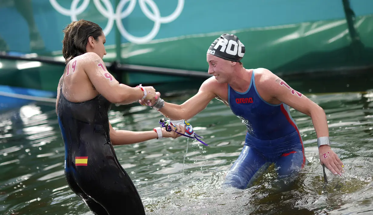 Atlet Spanyol Paula Ruiz Bravo (kiri) membantu atlet Komite Olimpiade Rusia Anastasiia Kirpichnikova setelah mereka selesai dalam renang maraton putri Olimpiade Tokyo 2020 di Tokyo, Jepang, 4 Agustus 2021. (AP Photo/David Goldman)