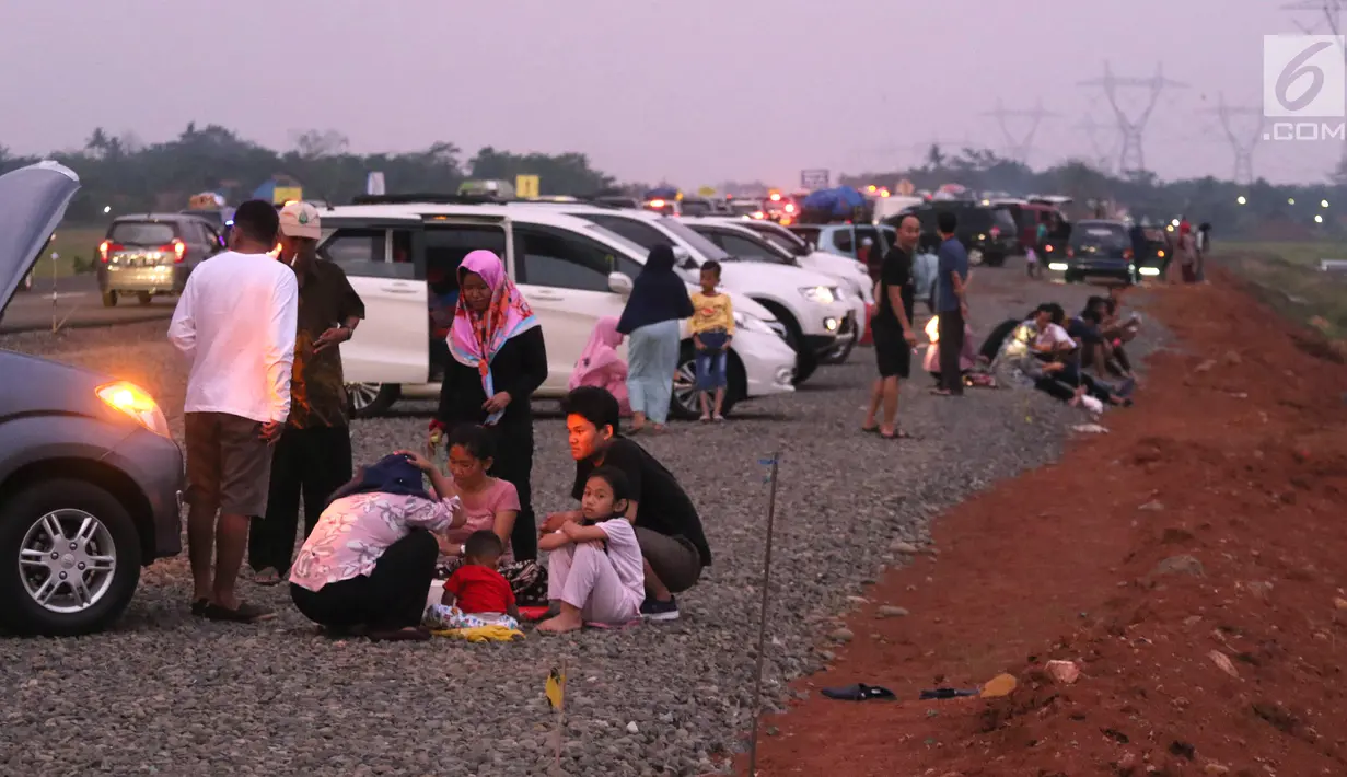 Pemudik menyantap hidangan berbuka puasa di pinggir Tol Fungsional Pemalang-Batang, Jawa Tengah, Minggu (10/6). Sambil berbuka mereka juga mendinginkan kendaraannya. (Liputan6.com/Arya Manggala)
