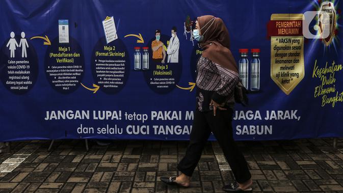 Seorang wanita berjalan melintasi lokasi penyuntikkan vaksin COVID-19 Sinovac kepada tenaga kesehatan di Puskesmas Palmerah, Jakarta, Kamis (28/1/2021). Pemberian vaksin COVID-19 tahap kedua dilaksanakan terhadap tenaga kesehatan mulai hari ini. (Liputan6.com/Johan Tallo)